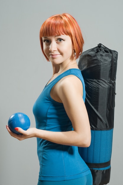 Red-haired fitness girl with yoga mat
