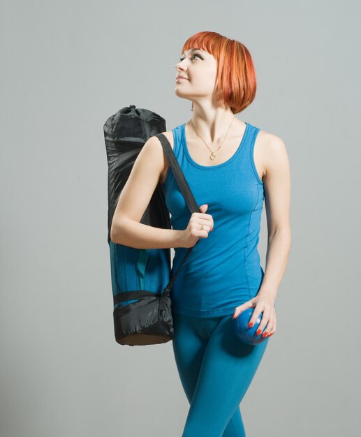 Red-haired fitness girl with yoga mat