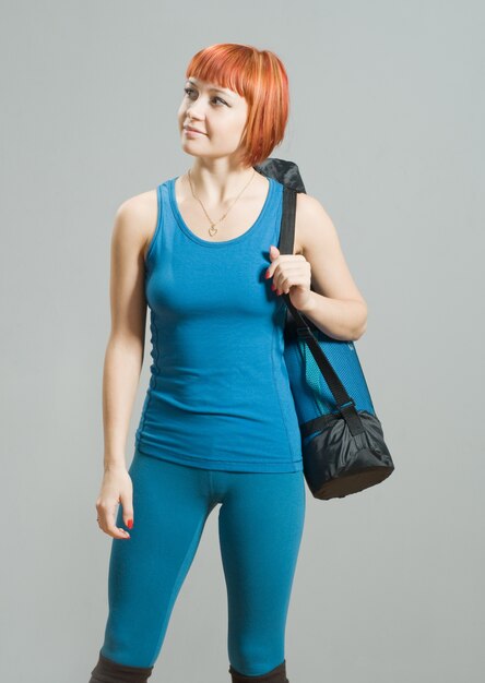 Red-haired fitness girl with yoga mat