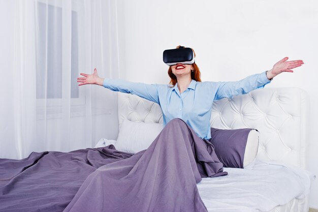 Red haired girl in bed with vr glasses at studio room