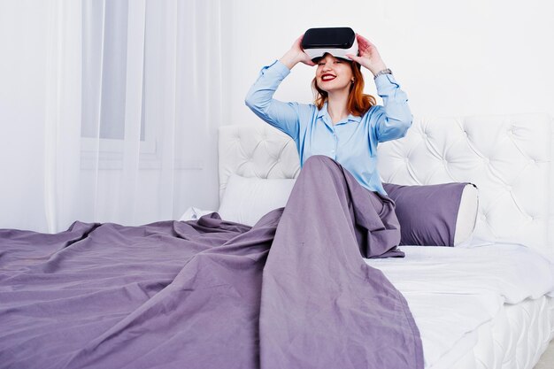 Free photo red haired girl in bed with vr glasses at studio room