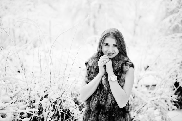 Red haired girl in fur coat walking at winter snowy park