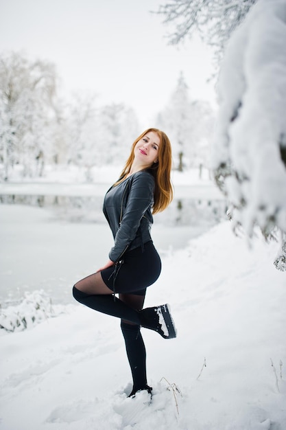 Red haired girl in fur coat walking at winter snowy park