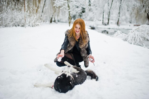 겨울날 허스키 강아지와 함께 공원에서 산책하는 빨간 머리 소녀
