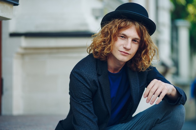 Red haired hipster man sitting on stairs posing