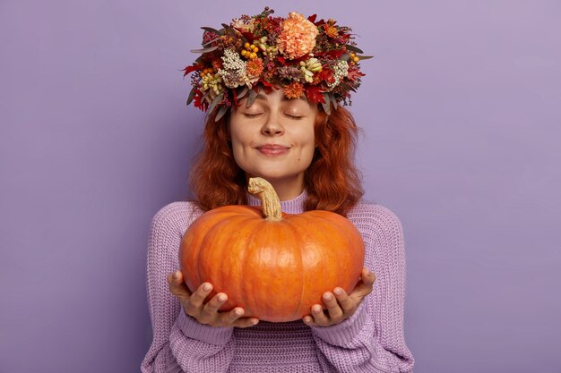 Red haired pensive content lady holds big ripe pumpkin
