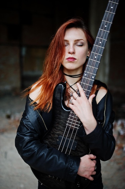 無料写真 赤い髪のパンクの女の子は、廃墟の場所でベースギターと黒に着るゴシック女性ミュージシャンの肖像画