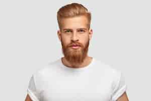 Free photo red haired serious young man blogger looks confidently