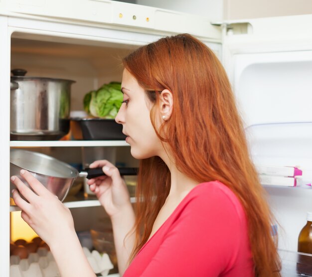 Red-haired woman looking for something in fridge