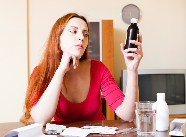 Free Photo red-haired woman reading about medications in manual at home