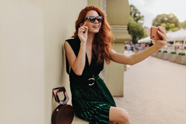 Selfie를 복용하는 세련 된 선글라스에 빨간 머리 여자