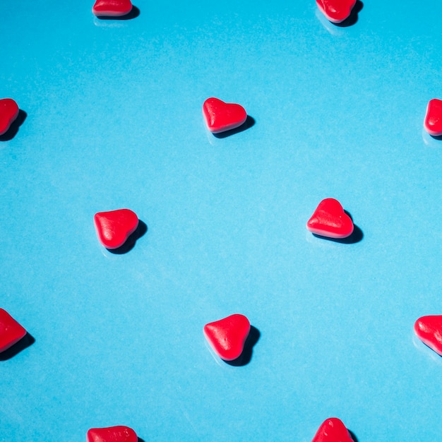 Red heart shape candies on blue background