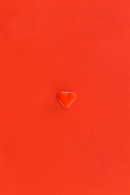 Red heart shape candy at the center of red background