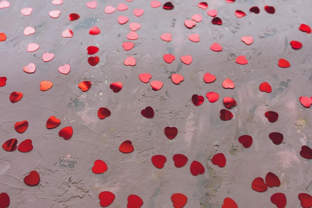 Red hearts confetti on rough concrete moody pink festive backround love dating and st valentines day
