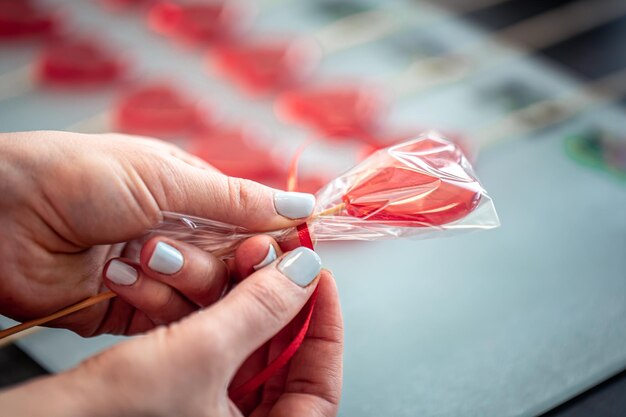 Red heartshaped lollipop in female hands close up