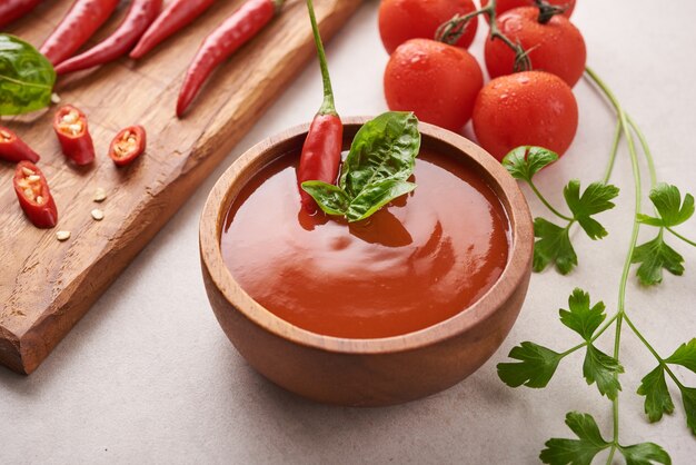 Red hot chilli sauce. tomato ketchup, chilli sauce, puree with chili pepper, tomatoes and garlic. on wooden cutting board on stone surface. top view.