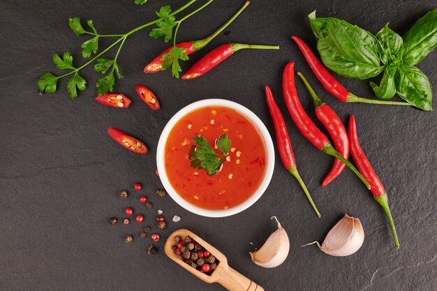 red hot chilli sauce. tomato ketchup, chilli sauce, puree with chili pepper, Vegetables, tomatoes and garlic. on on Black stone surface. top view