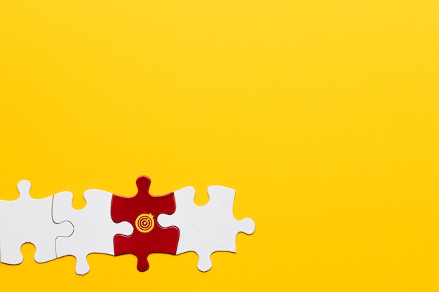 노란색 배경에 흰색 조각으로 배열 된 다트 판이 기호로 빨간 직소 퍼즐 조각