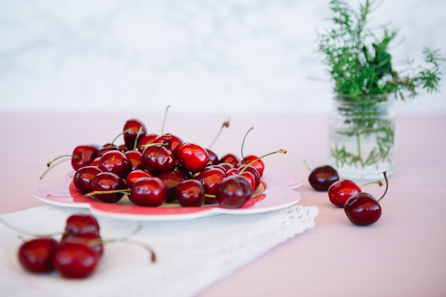 Red juicy cherries on plate over pink desk