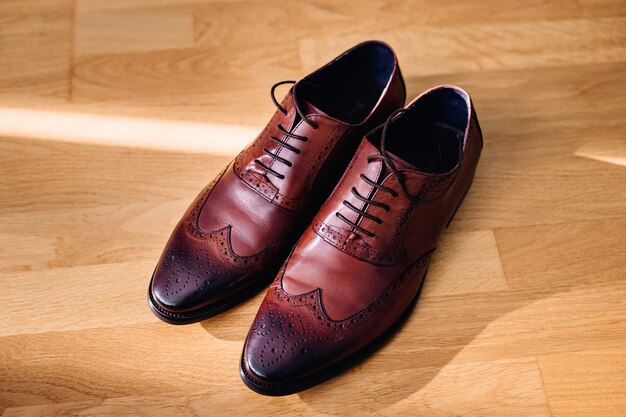 Red leather shoes stand on the light wooden floor