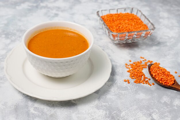 Red lentil cream soup on light  in white bowl,top view