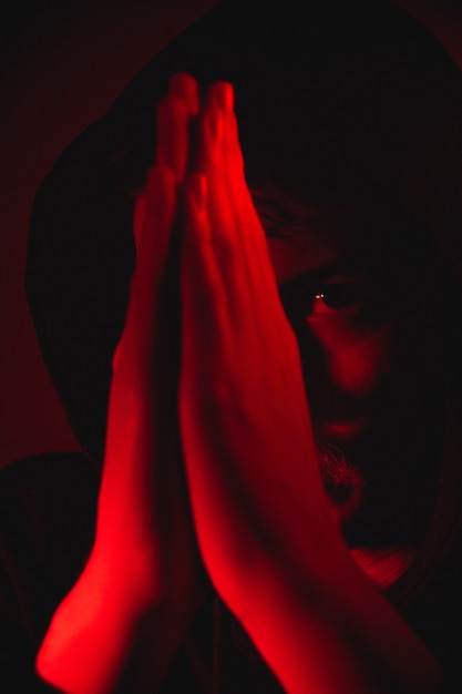 Red light over man with hands in prayer