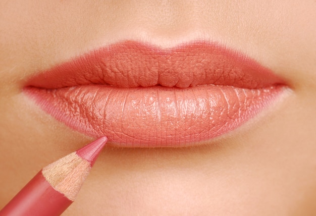 赤い口紅化粧鉛筆。メイクツール。女性の唇をクローズアップ