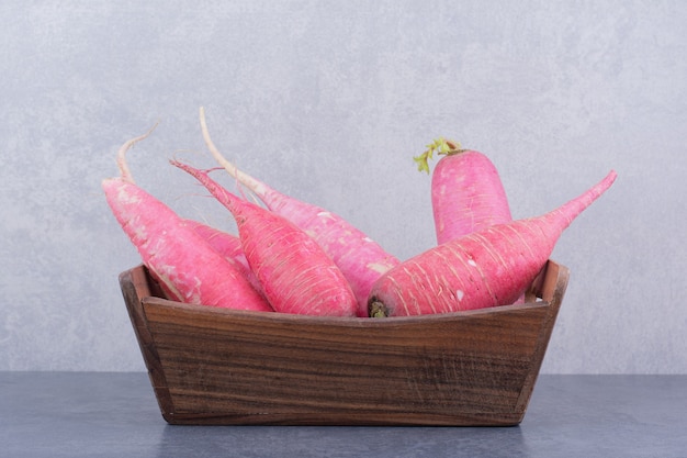 Free photo red long radishes on a wooden tray