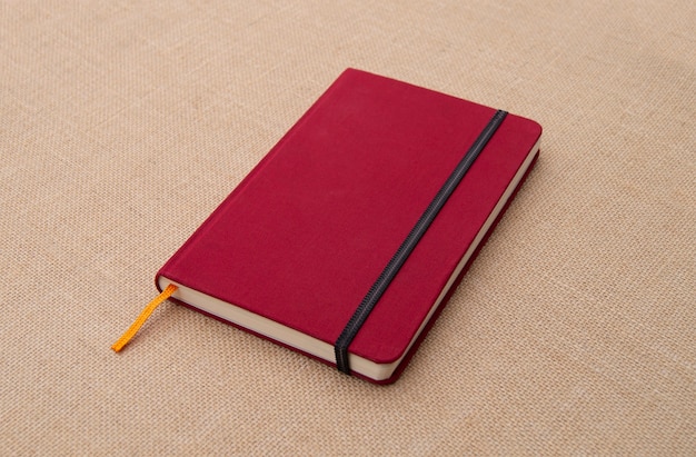 Free photo red notebook on fabric surface