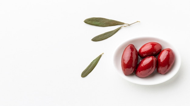 Red olives on plate with leaves with copy space