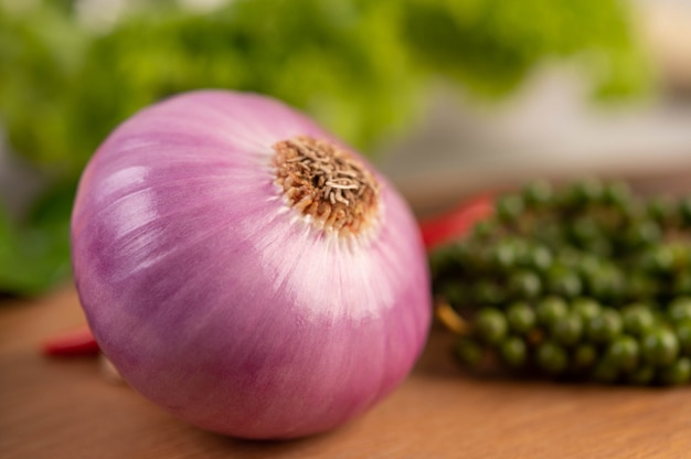 Free photo red onions and fresh pepper on wooden table.