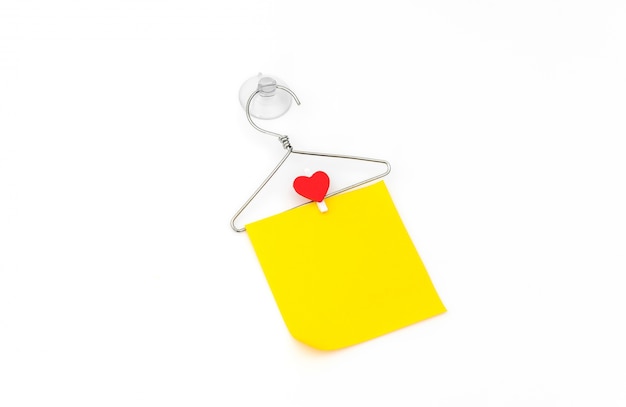 Red paper heart hanging on white background .