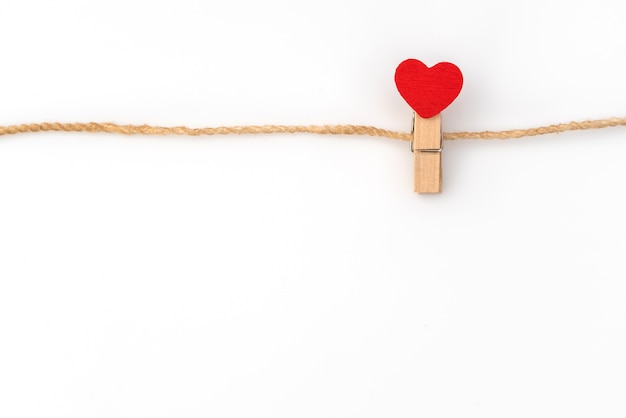 Red paper heart hanging on white background .