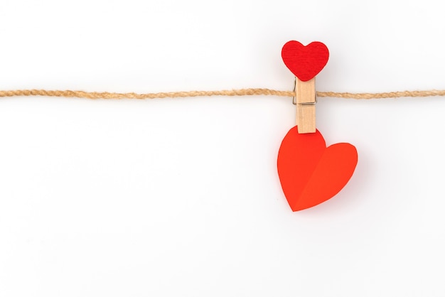 Red paper heart hanging on white background .