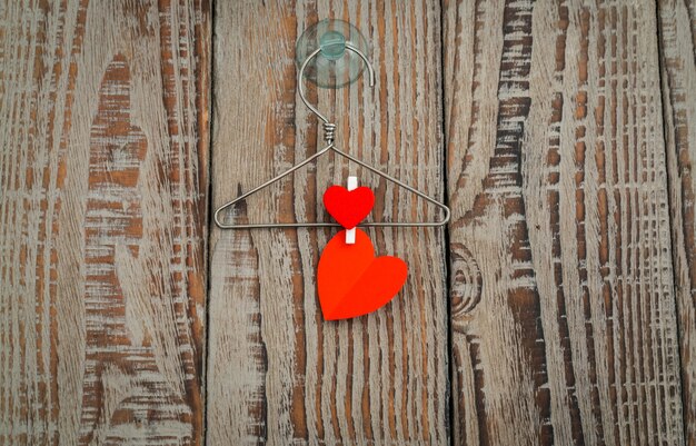 Red paper heart hanging on wood background .