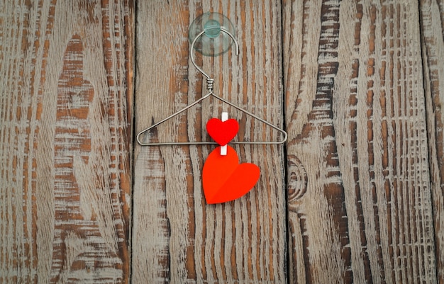 Red paper heart hanging on wood background .