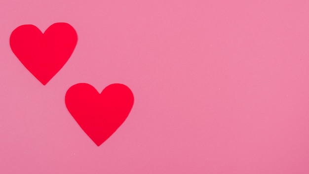 Red paper hearts on pink table 