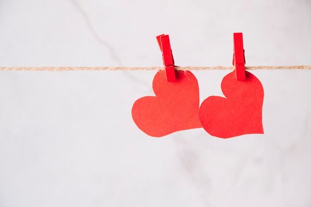 Red paper hearts with pins hitching on thread