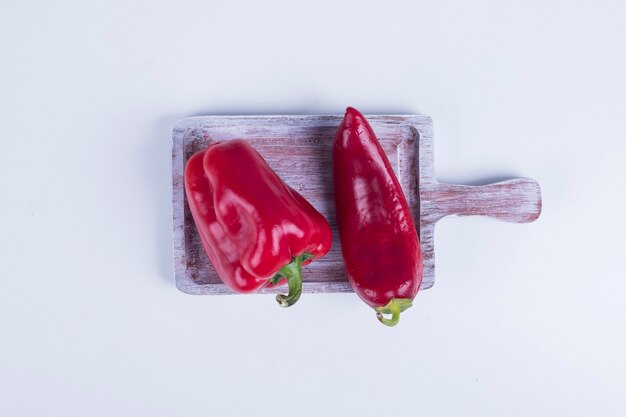 Red paprika and bell pepper on a wooden board in the middle