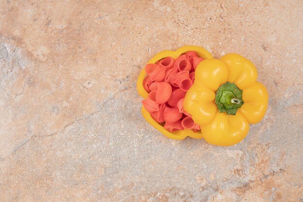 Red pasta in bell pepper on orange background