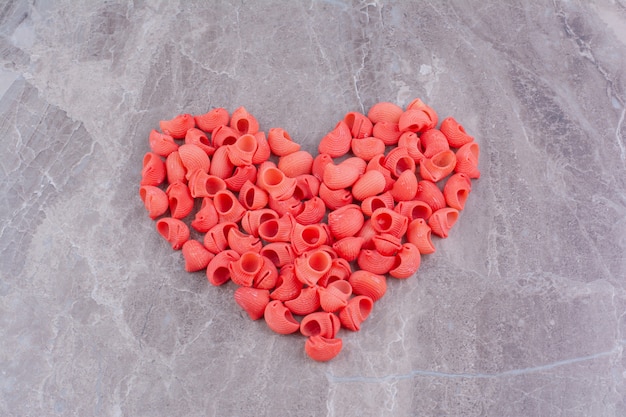 Red pastas in a heart shape on the marble surface