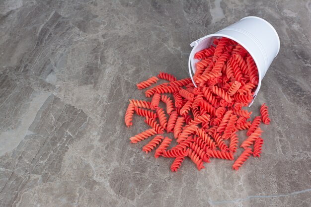 Red pastas out of a metallic white bucket. 