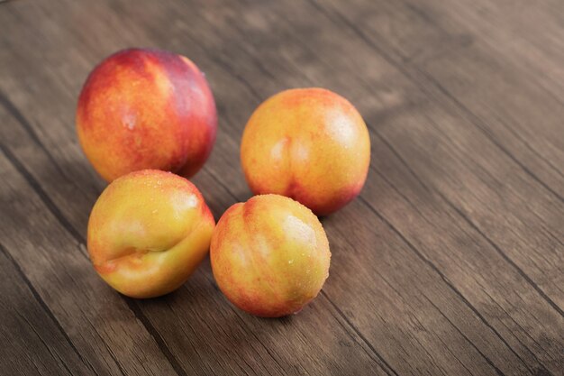 Red peaches isolated on wooden board.