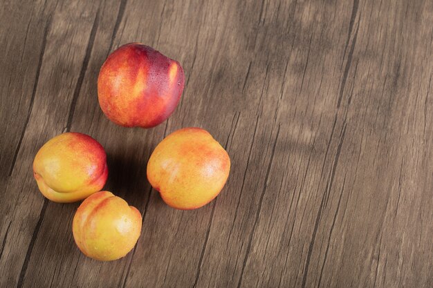 Red peaches isolated on the wooden table. 