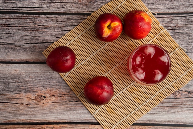 Foto gratuita pesche rosse con una tazza di bevanda ghiacciata