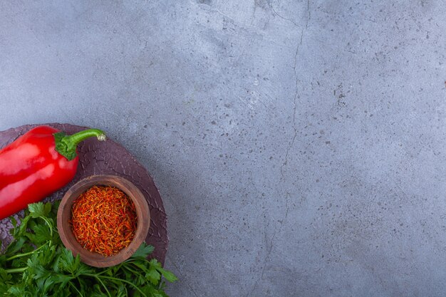 Red pepper, parsley leaves and cherry tomatoes on wood piece.