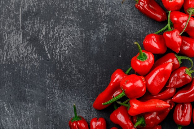 Red peppers on dark grunge wall, flat lay.