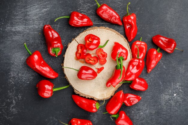 Red peppers on a wooden piece on a grungy grey wall. top view.