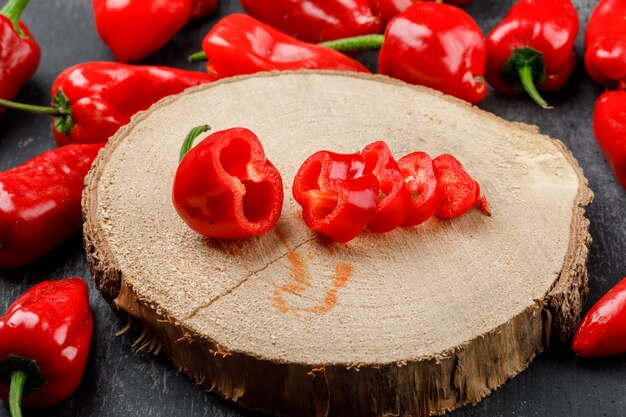 Red peppers on a wooden piece high angle view on a grungy grey wall