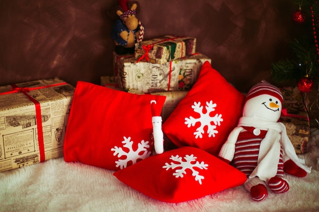 Red pillows with snowflakes and toy snowman lie on the floor 